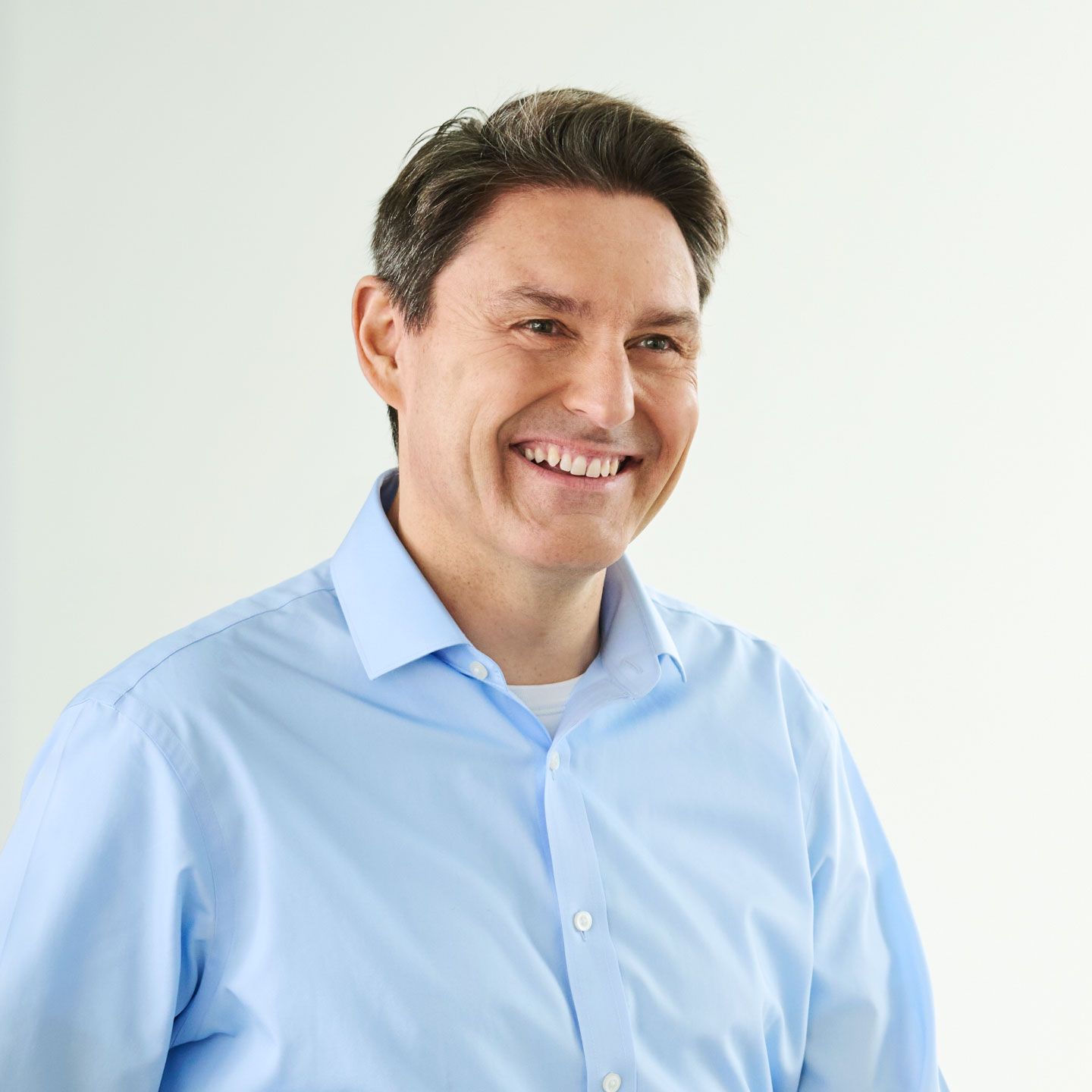 Stephan Ohlmeyer, man standing smiling in a light-blue shirt in a bright room