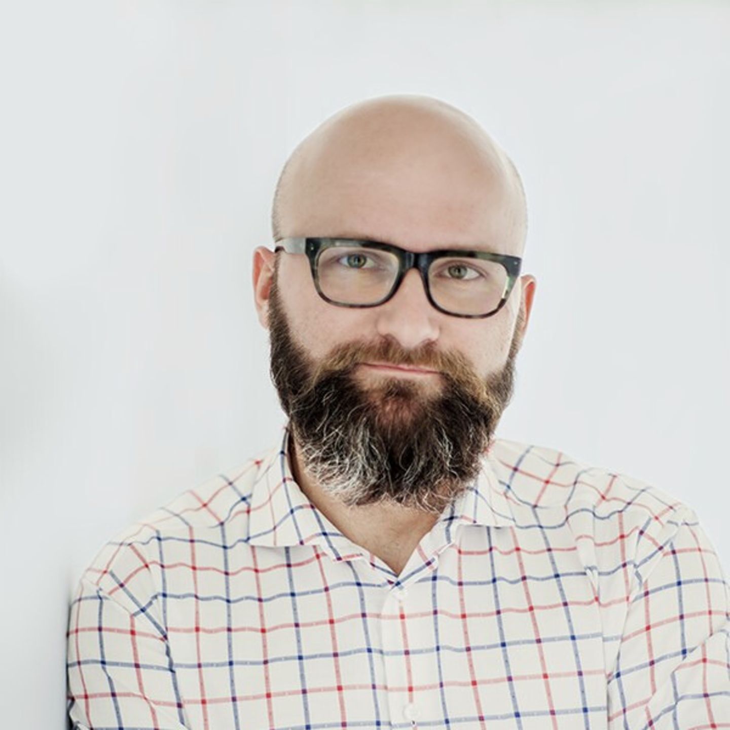 Dr hab. Tomasz Piekot Dr hab. Tomasz Piekot with a plaid button-down shirt leaning against a white wall