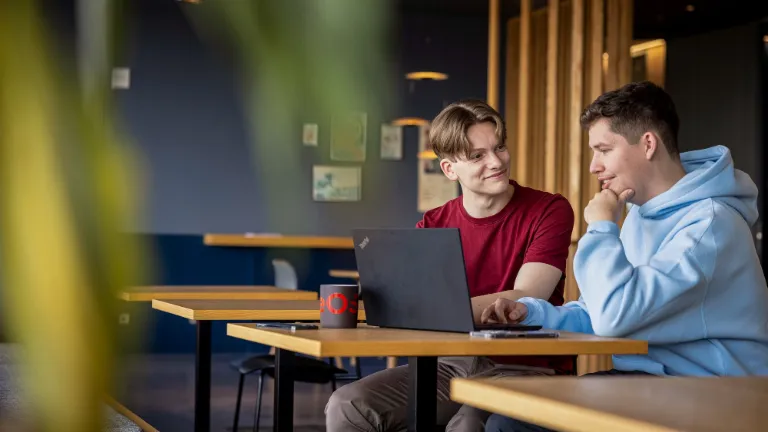 Two employees collaborating on a laptop, promoting partnership and fairness in the workplace